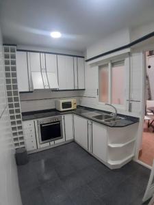 a kitchen with white cabinets and a sink and a microwave at APARTAMENTO PATRICIA in Murcia
