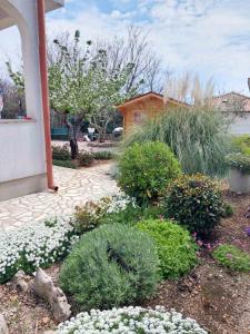 um jardim com flores e plantas em frente a uma casa em Rooms Hodanić em Krk