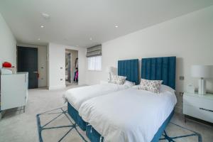 a large bedroom with two beds with blue curtains at ALTIDO Spectacular flat overlooking river Thames in London