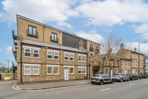 a brick building with cars parked in front of it at ALTIDO Spectacular flat overlooking river Thames in London