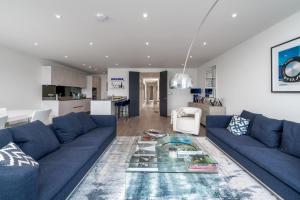a living room with a blue couch and a table at ALTIDO Spectacular flat overlooking river Thames in London