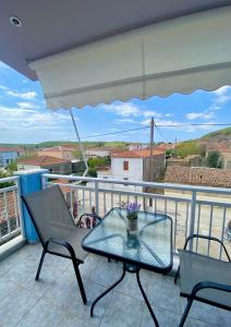 a patio with a glass table and chairs on a balcony at Theodora’s Studios in Repanídhion