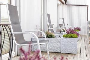 une rangée de chaises sur un balcon avec des plantes dans l'établissement Hotel Garni Haus zum Gutenberg, à Hallbergmoos