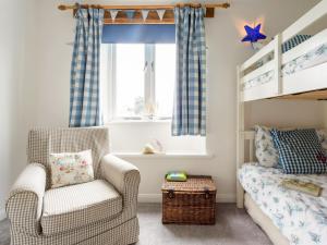 a childs bedroom with a chair and a bunk bed at Rose Cottage in Stoke Fleming