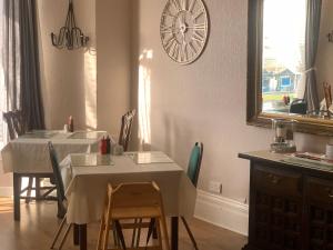 a dining room with a table and a clock on the wall at Bella Vista in Llandudno