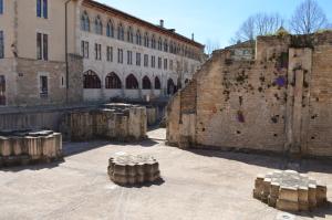 un gran edificio de ladrillo con algunos troncos en un patio en Hotel de Bourgogne en Cluny