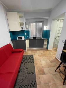 a living room with a red couch and a kitchen at Perugia Home Apartment La Finestra Di Fronte in Perugia