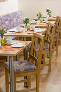 uma fila de mesas e cadeiras de madeira num quarto em Hotel Garni Haus zum Gutenberg em Hallbergmoos