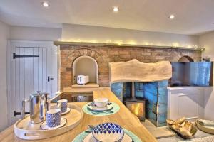a kitchen with a wooden table and a fireplace at The Snug at Ruston, Cosy Dog Friendly Cottage in Wykeham