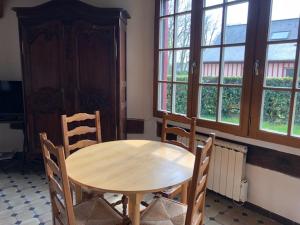 una mesa de madera y sillas en una habitación con ventanas en le colombier de Royaumont, en Saint-Arnoult