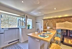 a kitchen with a table and a fireplace at The Snug at Ruston, Cosy Dog Friendly Cottage in Wykeham