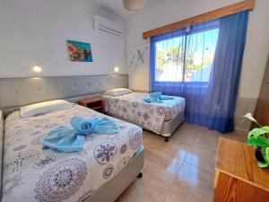 two beds in a room with a window at Florence Hotel Apartments in Ayia Napa