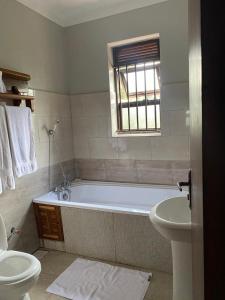 a bathroom with a tub and a toilet and a sink at Golden Cherries Guest House in Jinja