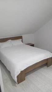 a bed with white sheets and a wooden frame at Cazare Paiu VasiVasi in Vaslui