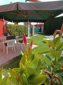 um pátio com uma mesa e um guarda-chuva verde em Costalaguna Briccola con 3 camere da letto em Cavallino-Treporti