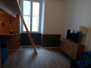 Una sala de estar con un televisor sobre una cómoda y una ventana. en Appartement rue de la cascade 64440 Eaux-Bonnes, en Eaux-Bonnes