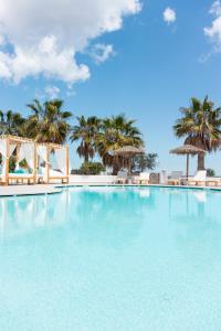 ein großer Pool mit Palmen im Hintergrund in der Unterkunft Casa Vitae Suites in Kamari