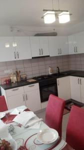 a kitchen with white cabinets and red chairs and a table at Cazare Paiu VasiVasi in Vaslui