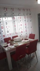 a dining room table with red chairs and a white curtain at Cazare Paiu VasiVasi in Vaslui