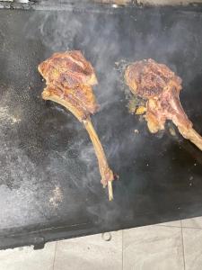 two pieces of meat cooking on a grill at Pensiunea Trei Lalele in Moisei