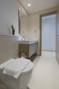 a white bathroom with a toilet and a sink at Harbour Gate 1 - 2BR Apartment - Allsopp&Allsopp in Dubai