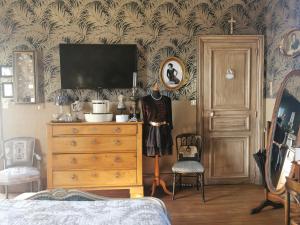 um quarto com uma cómoda e uma televisão e uma cómoda com uma televisão em VILLA LES CAMELIAS em Fontaine-lès-Vervins