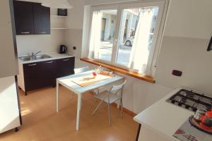una pequeña cocina con una mesa blanca y una ventana en ~ La Villetta Gialla ~ Casa al centro del F.V.G, en Rodeano Basso