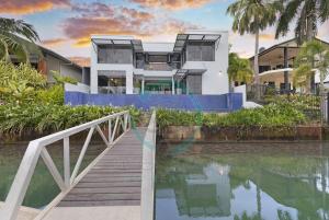 uma casa com uma ponte sobre um corpo de água em ZenLux: 4BR Bayview Mansion Infinity Pool + Cinema em Stuart Park