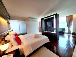 a bedroom with a white bed with red pillows and a television at Nordwind Hotel in Chiang Mai