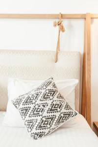 a white bed with a black and white pillow on it at Casa Vitae Suites in Kamari