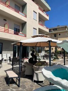 eine Terrasse mit Tischen, Stühlen und einem Sonnenschirm in der Unterkunft Hotel Cristina in Chianciano Terme