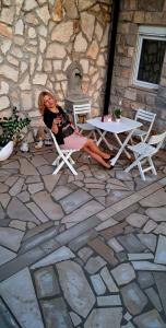 a woman sitting in a chair next to a table at APARTMANI DIJANA in Trebinje