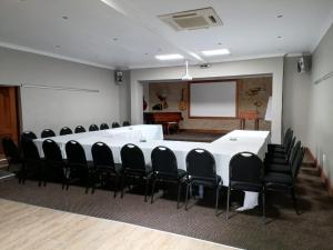 uma sala de conferências com uma mesa branca e cadeiras pretas em Issaquena Heights Boutique Hotel em Knysna