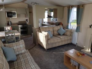 a living room with two couches and a kitchen at 6 BERTH DELUXE CARAVAN PALM GROVE 42 in Chapel Saint Leonards