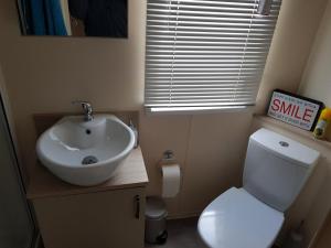 uma pequena casa de banho com lavatório e WC em 6 BERTH DELUXE CARAVAN PALM GROVE 42 em Chapel Saint Leonards
