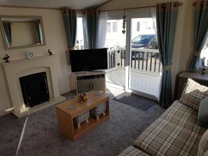 a living room with a tv and a fireplace at 6 BERTH DELUXE CARAVAN PALM GROVE 42 in Chapel Saint Leonards