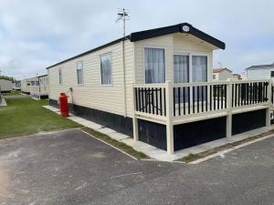 una casa con una valla blanca y una boca de incendios roja en 6 BERTH DELUXE CARAVAN PALM GROVE 42, en Chapel St. Leonards