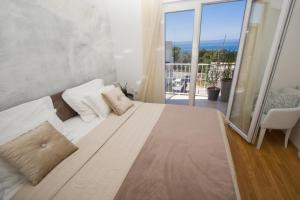 Cama blanca grande en habitación con balcón en Luxury apartment near the beach, en Makarska