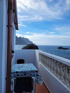 a balcony with a table and a view of the ocean at Room in Lodge - Beautiful Sunsets from the Balcony El Roque in Santa Cruz de Tenerife