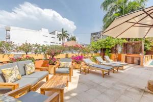 a patio with chairs and tables and an umbrella at 2cm-B1 Apartment In Getsemani With Air Conditioning Pool And WIFI in Cartagena de Indias