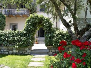 een huis met een tuin met rode bloemen ervoor bij B&B Casa del Nonno in Adrara San Rocco