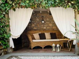 a wicker couch sitting on a patio with curtains at B&B Casa del Nonno in Adrara San Rocco
