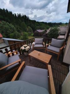 a deck with couches and a table and chairs at Spiski Apartament in Łapsze Niżne