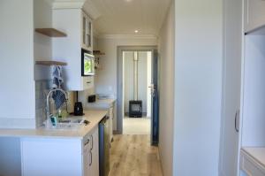 a kitchen with white cabinets and a hallway at Serenity Ocean Lodge in Wilderness