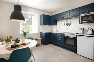 a kitchen with blue cabinets and a white counter top at Kincraig House - Seasgair Lodges in Kincraig