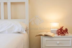sypialnia z łóżkiem i książką na stoliku nocnym w obiekcie Breezy Beach House w mieście Marina di Mancaversa