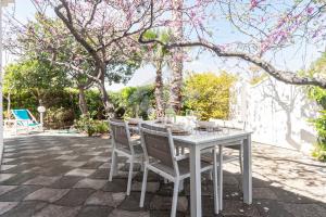 Biały stół i krzesła na patio z drzewami w obiekcie Breezy Beach House w mieście Marina di Mancaversa