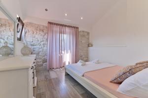a white bedroom with a bed and a window at Apartman Ciciliani in Trogir