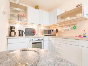 a kitchen with white cabinets and a marble counter top at Appartementhaus Sonnenbad - Luxuspenthouse App. 11 in Sassnitz