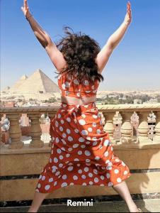 een vrouw in een polka dot jurk springend over een hek bij Crowne Pyramids view inn in Caïro